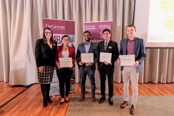 Group of people standing and smiling in a banquet hall, holding certificates that read "Co-op Student of the Year Nominees"