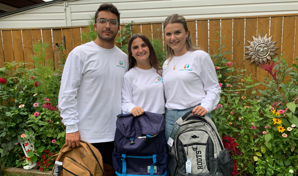 The Backpacks for Brainiacs team holds up backpacks.