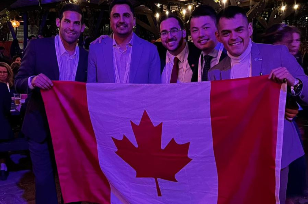 Canadian ambassadors and delegates standing in front of Canadian flag.