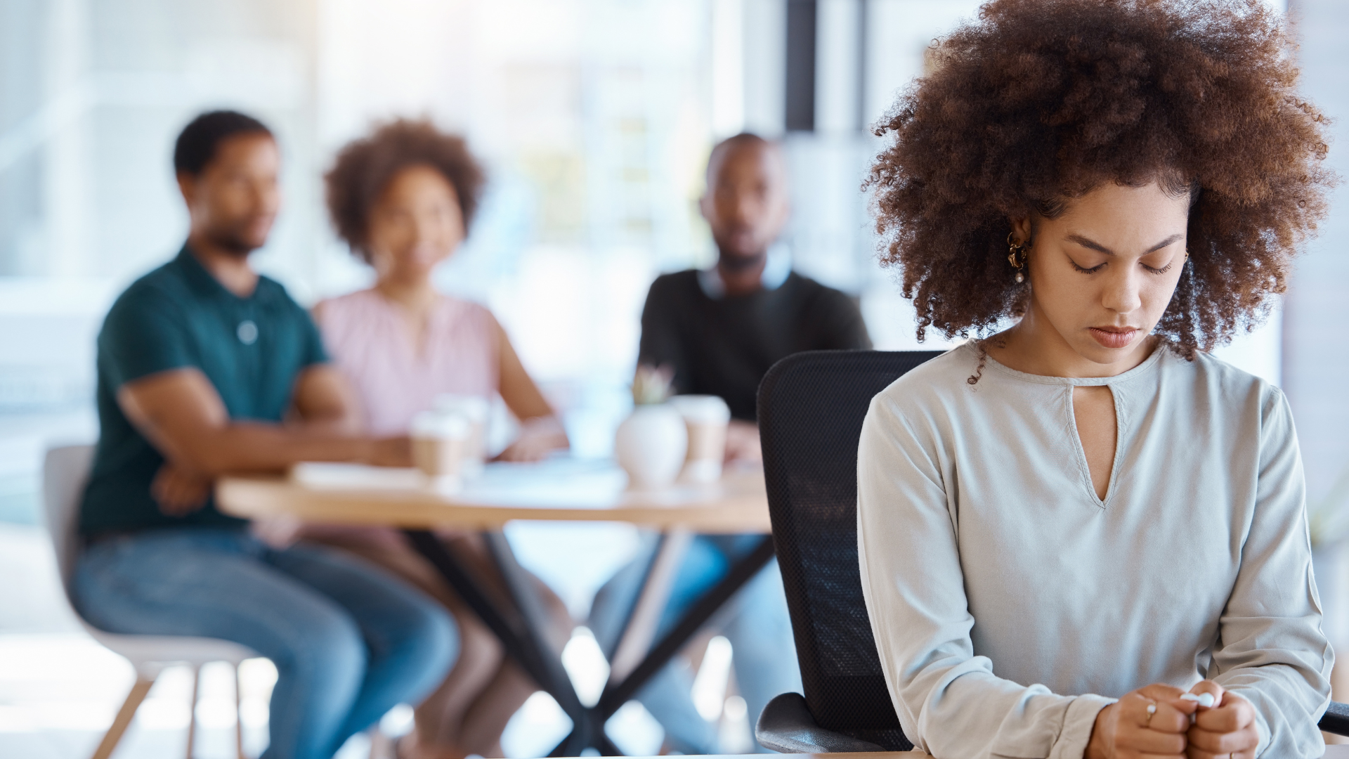 Employee sitting alone, not feeling part of the team.